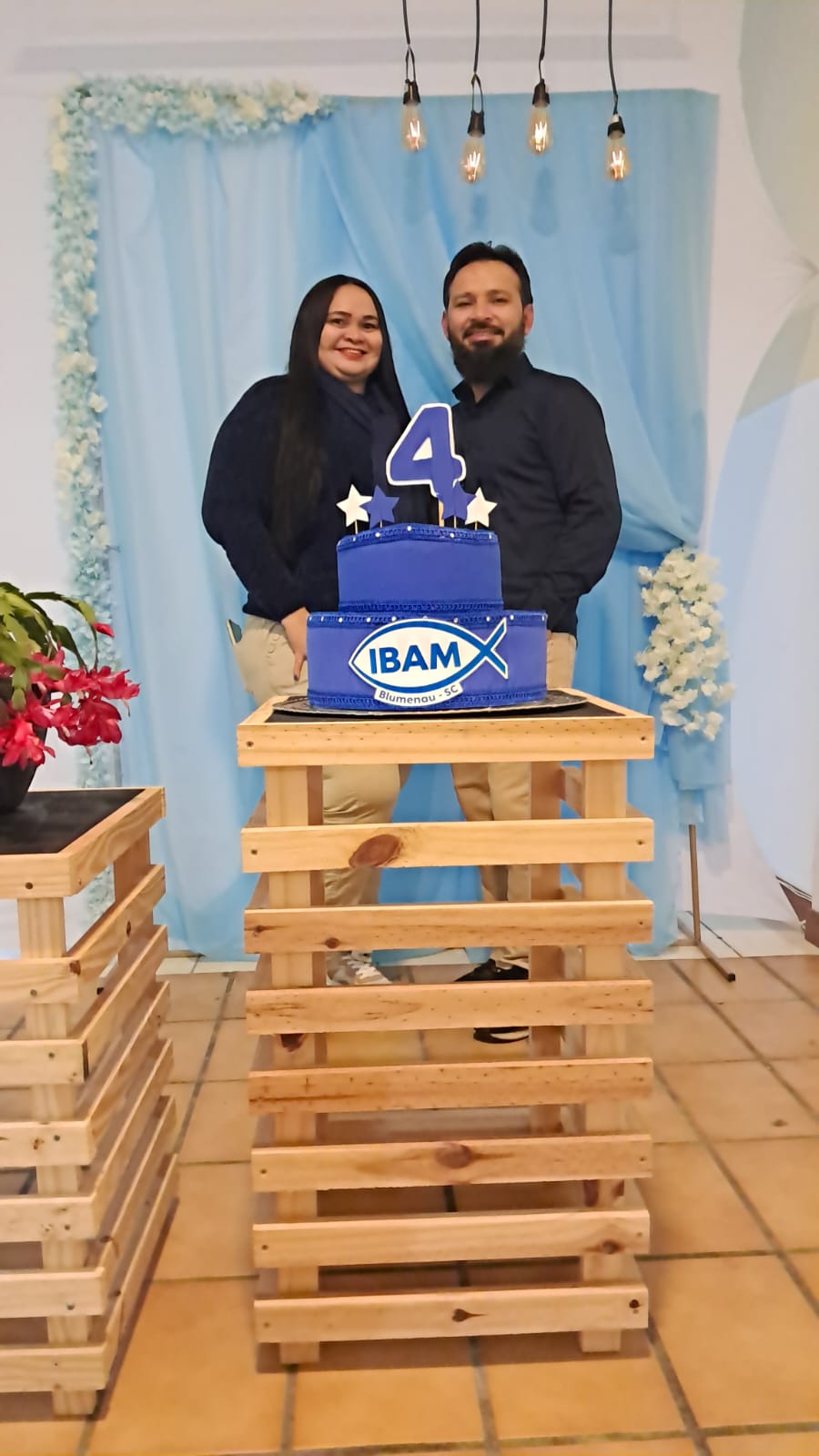 Casal posando ao lado do bolo dos 4 anos