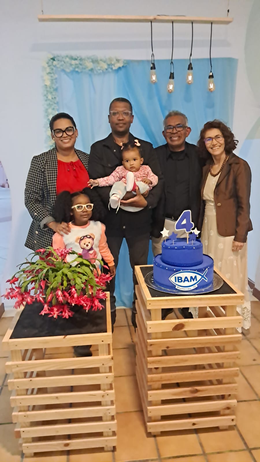 Família com bebê ao lado do bolo dos 4 anos da IBAM